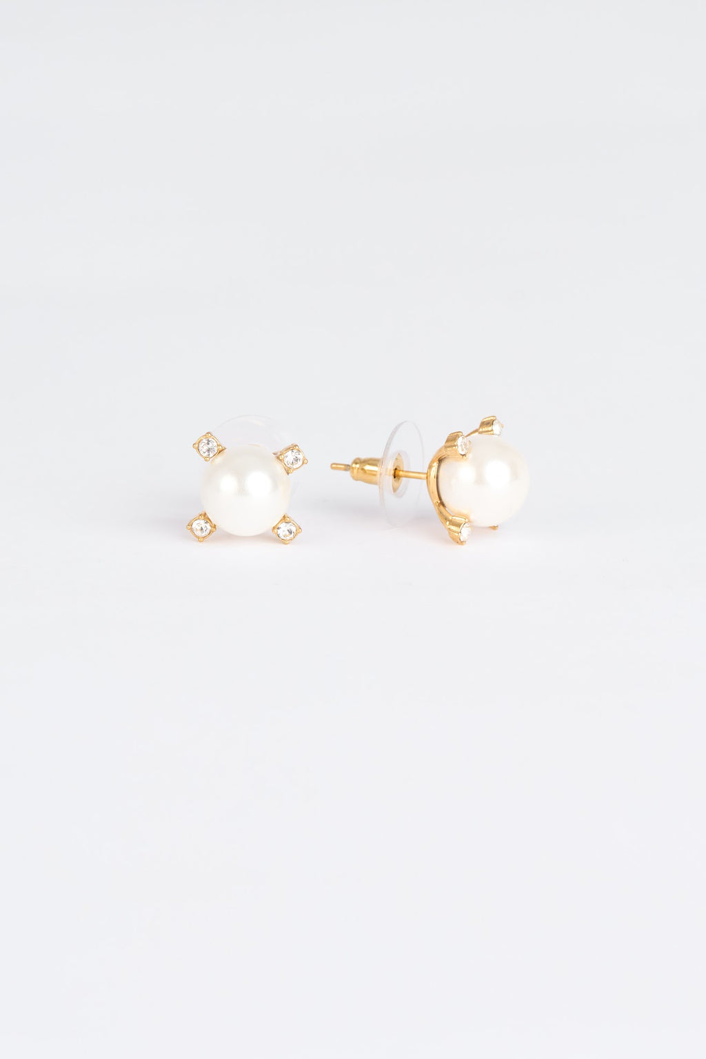 Pair of gold earrings with pearl-like centers on a light gray background