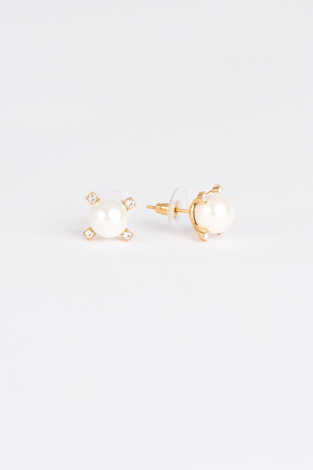 Pair of gold earrings with pearl-like centers on a light gray background