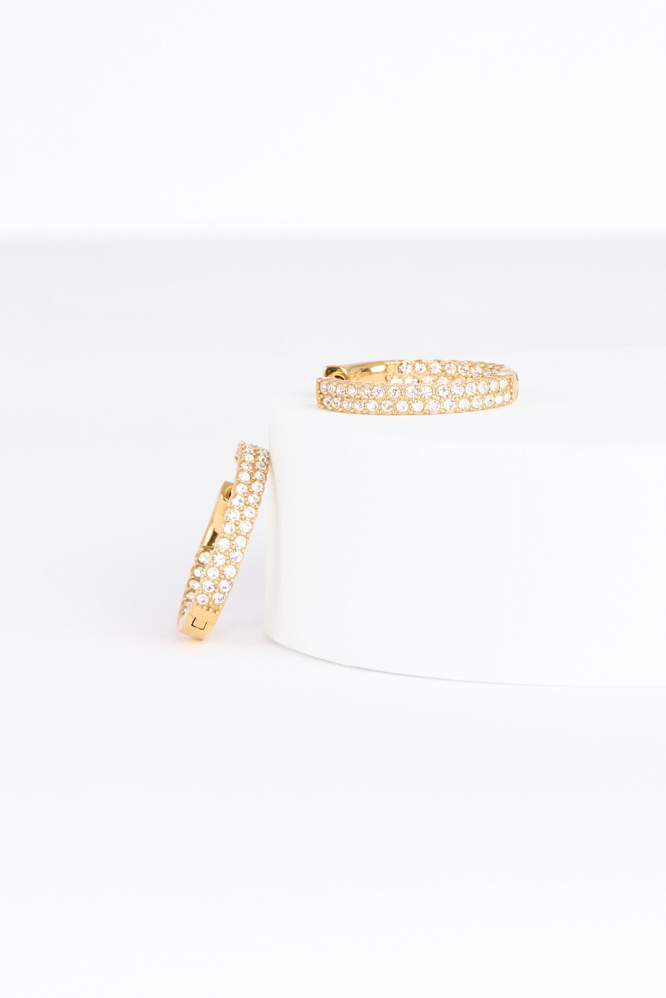 Two gold hoop earrings on a white background