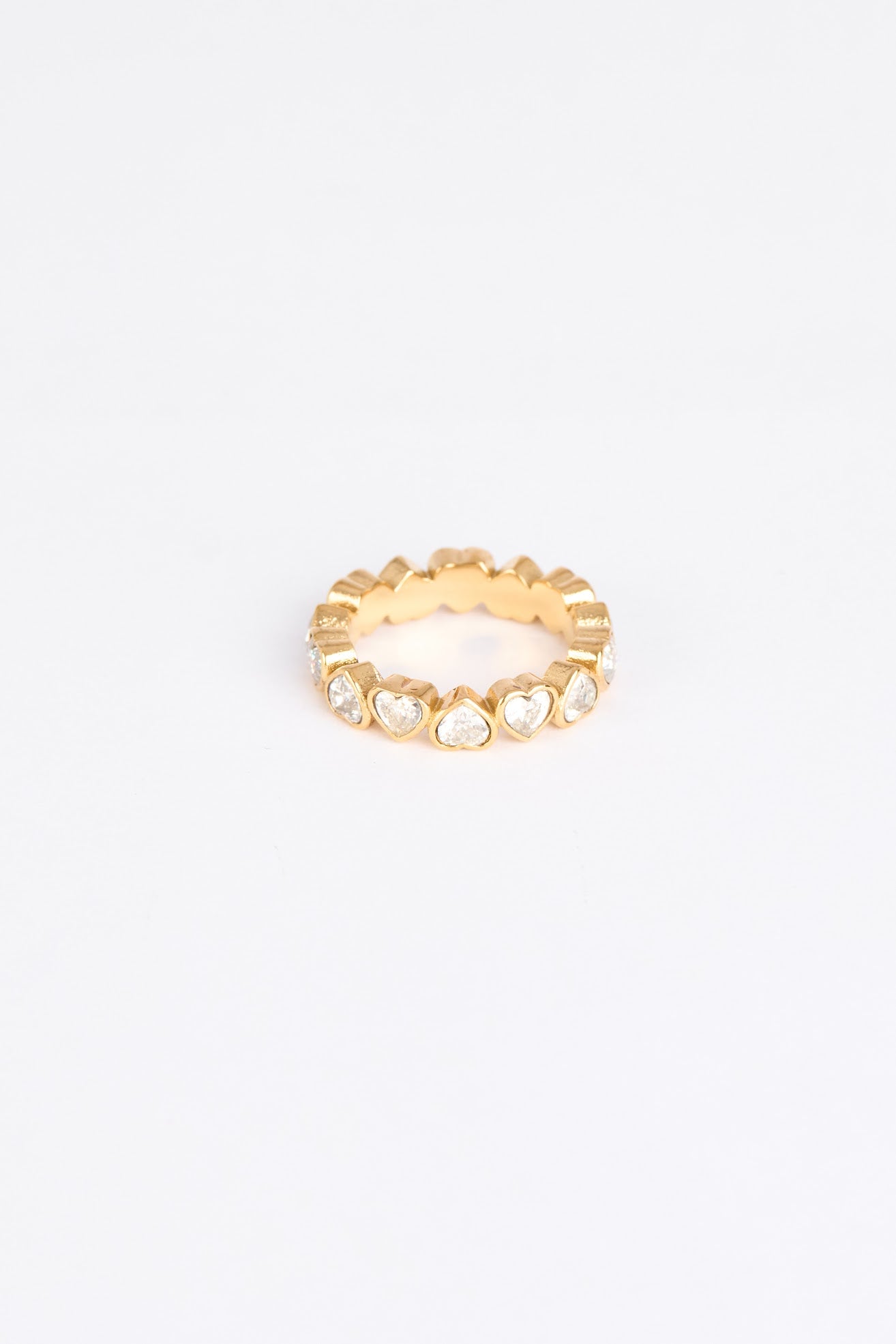 Gold ring with heart-shaped stones on a white background