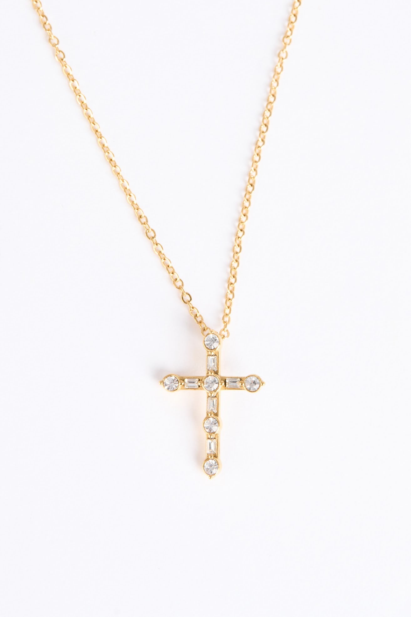 Gold cross necklace with small diamonds on a white background