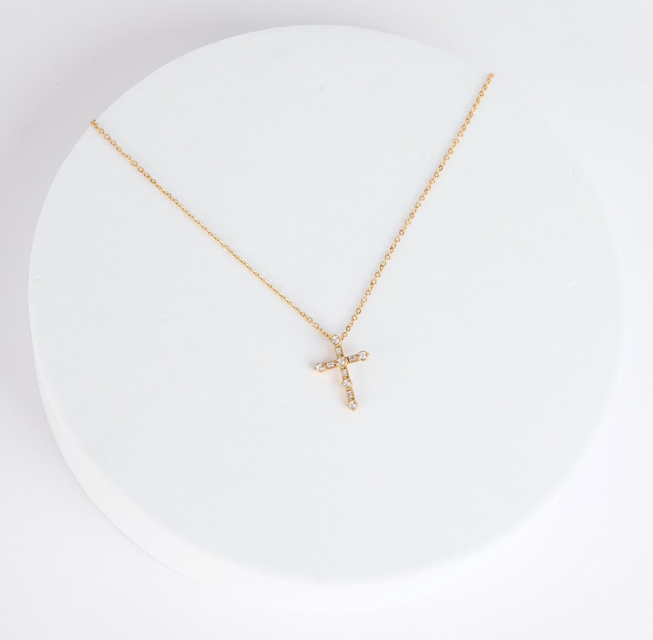 Gold necklace with a cross pendant on a white background